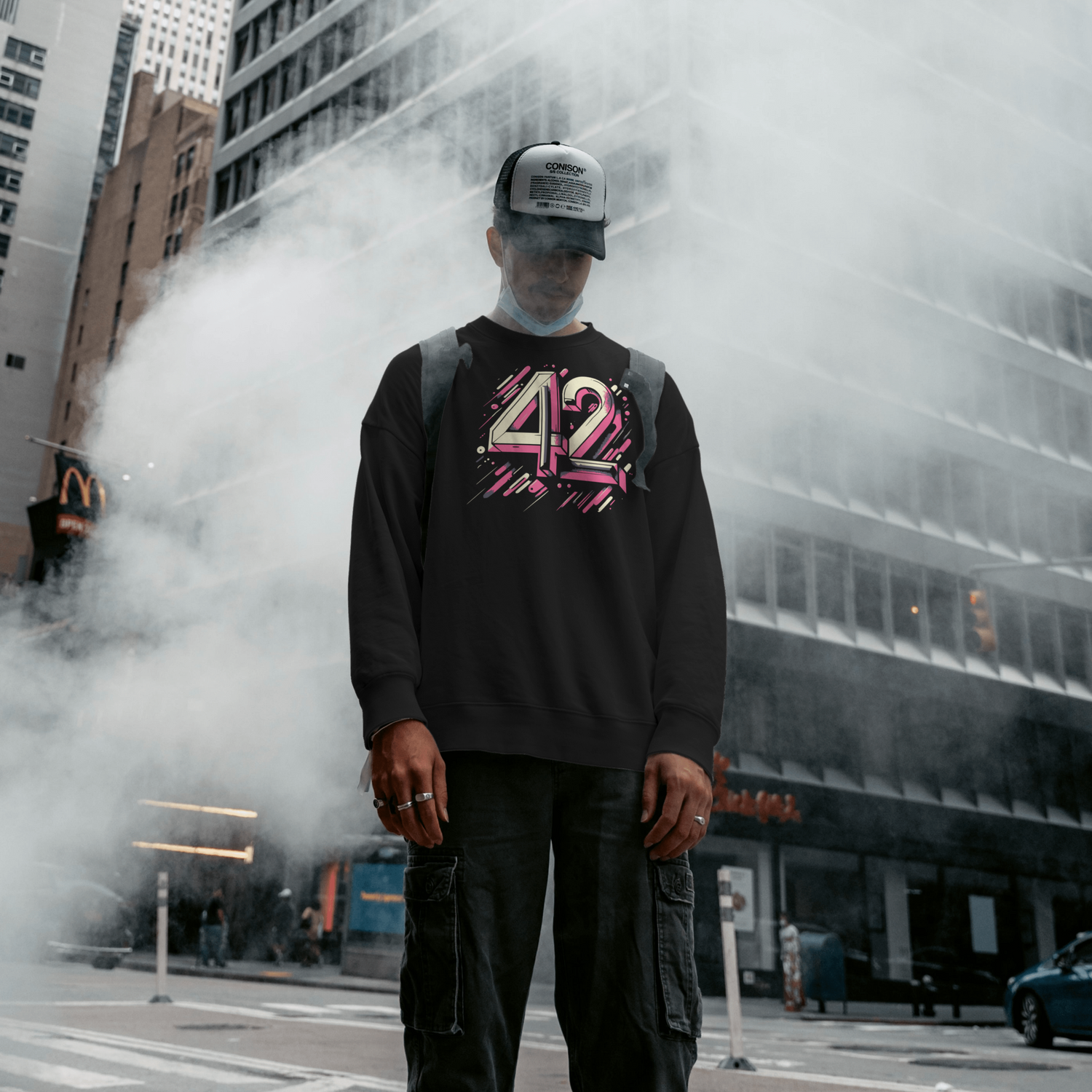 Ein Mann steht im Rauch und trägt einen schwarzen Pullover mit "42" Motiv