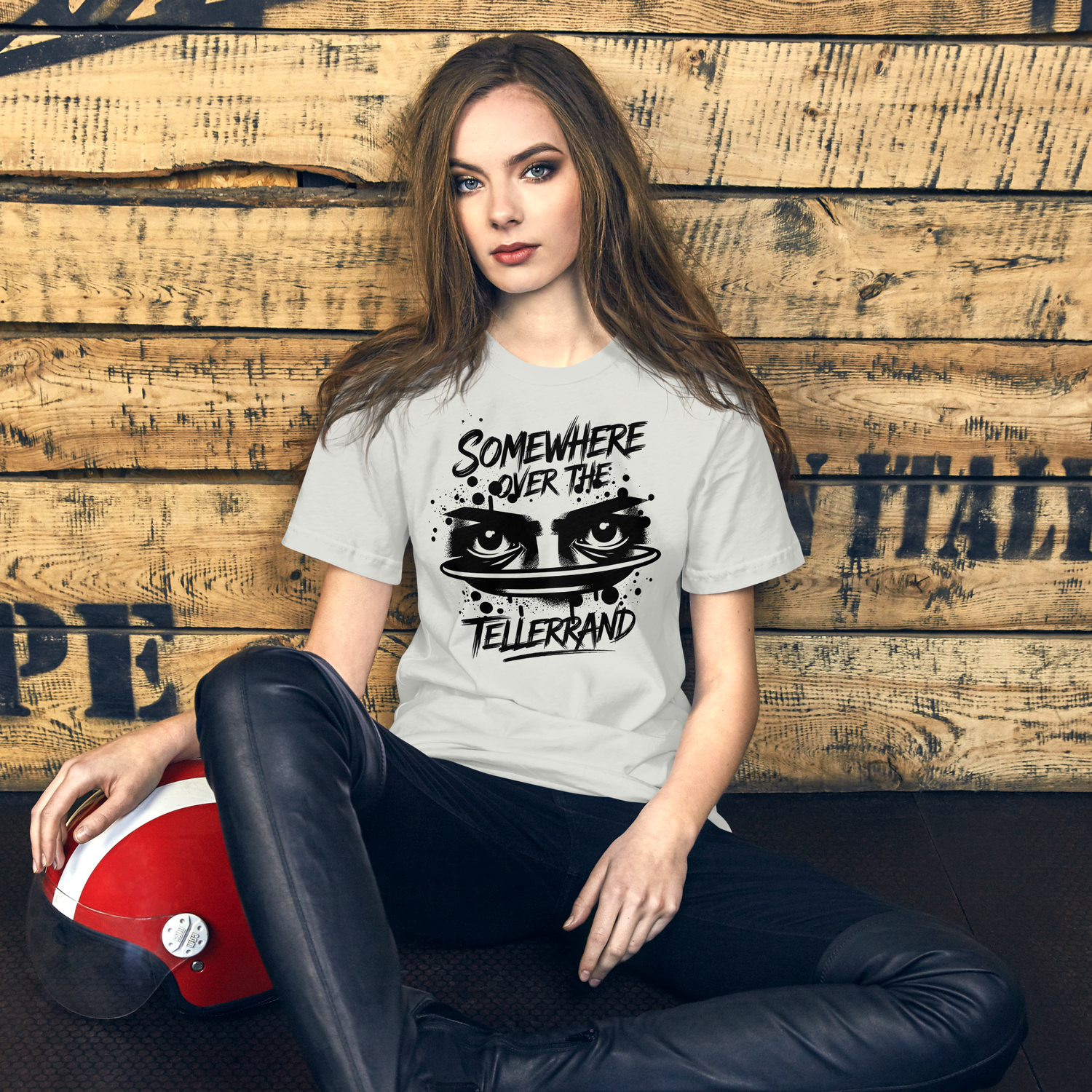 eine Frau trägt ein Shirt mit "Somewhere over the Tellerrand" Print, sitzt an Holzwand