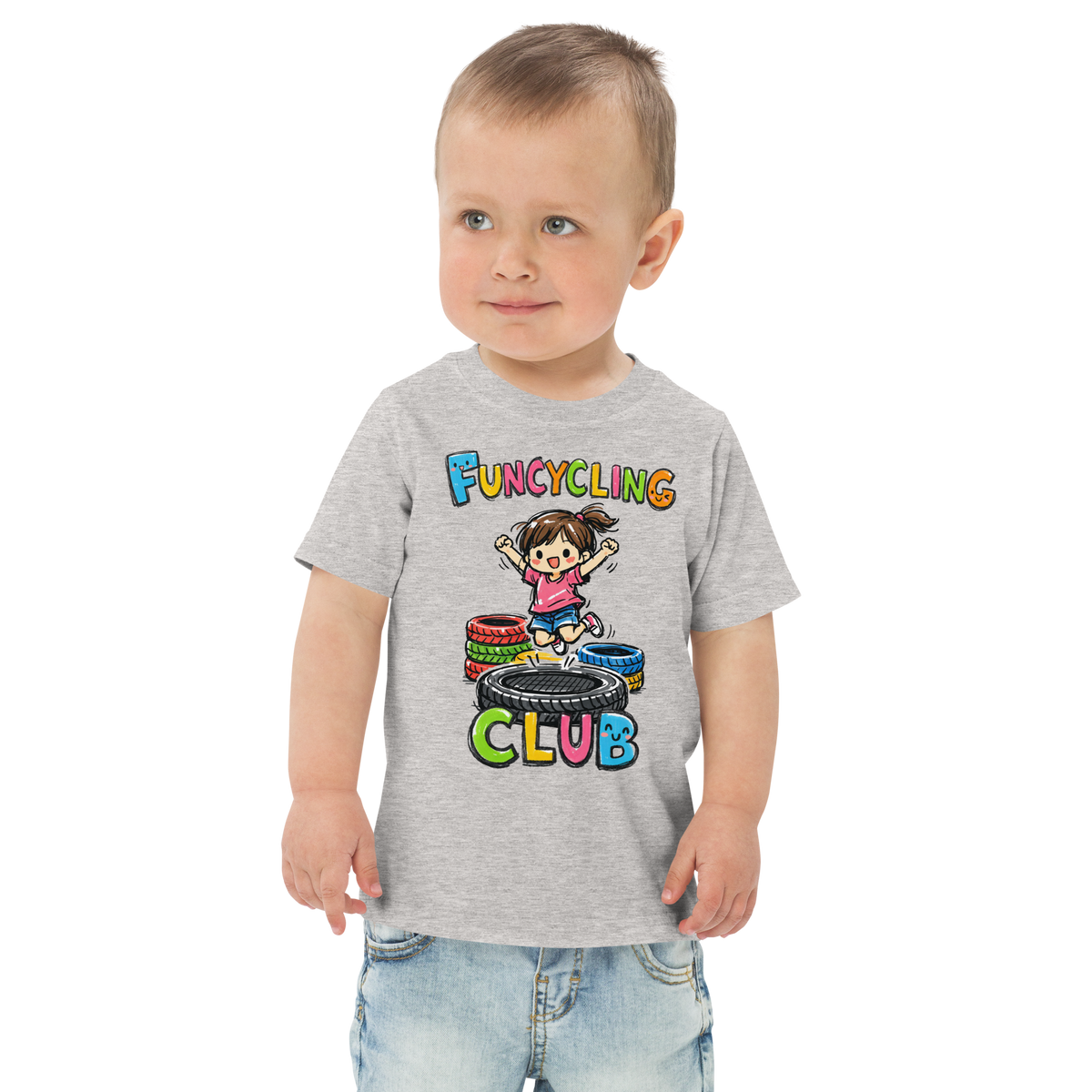 Ein Junge trägt ein graues T-Shirt mit buntem "Funcycling Club" Print und einem Mädchen, das auf einem Reifen Trampolin springt