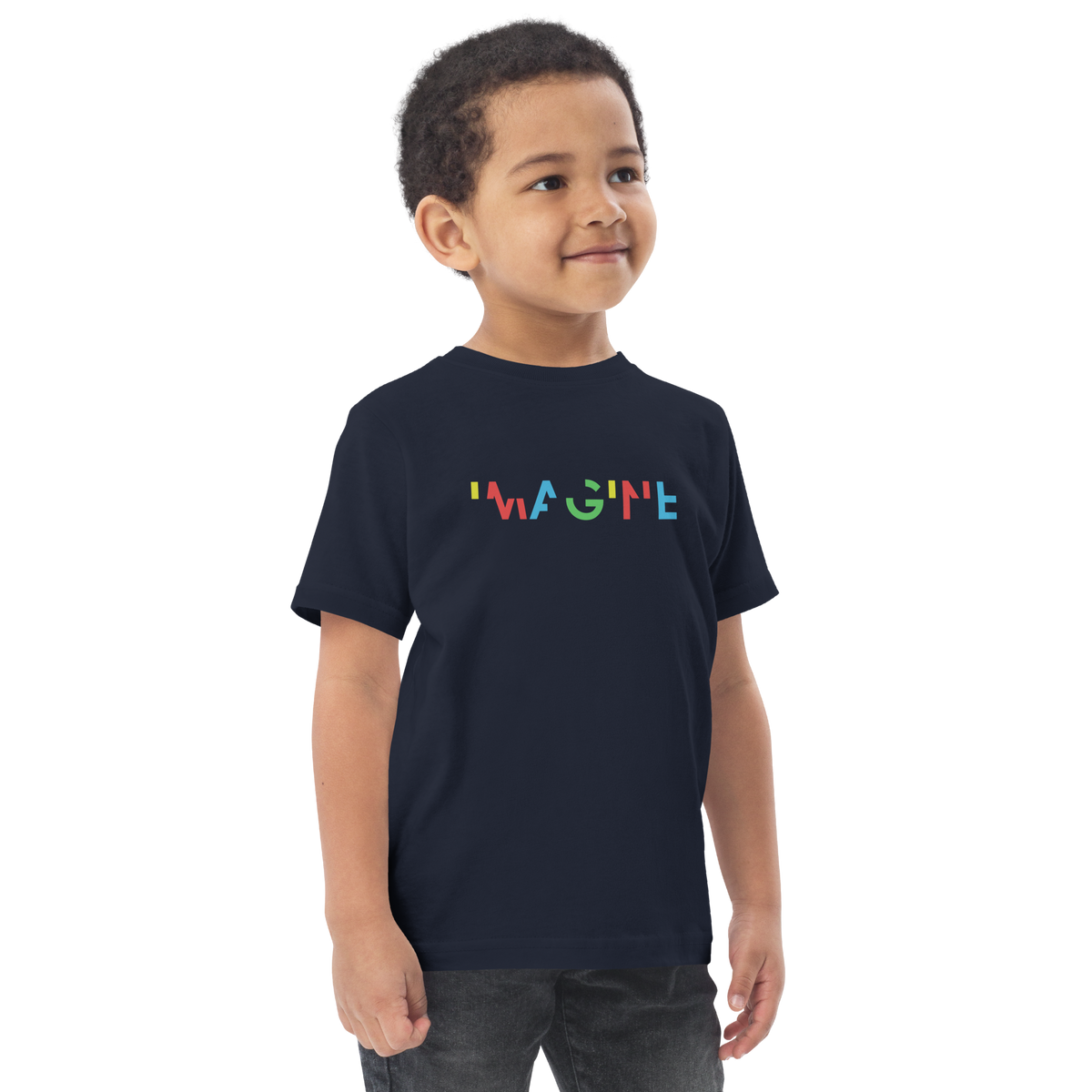 Kleiner Junge trägt blaues T-Shirt mit buntem IMAGINE Schriftzug