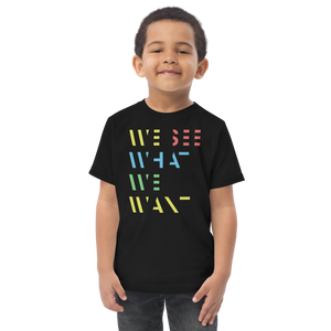 Junge trägt schwarzes T-Shirt mit buntem We See What We Want Schriftzug