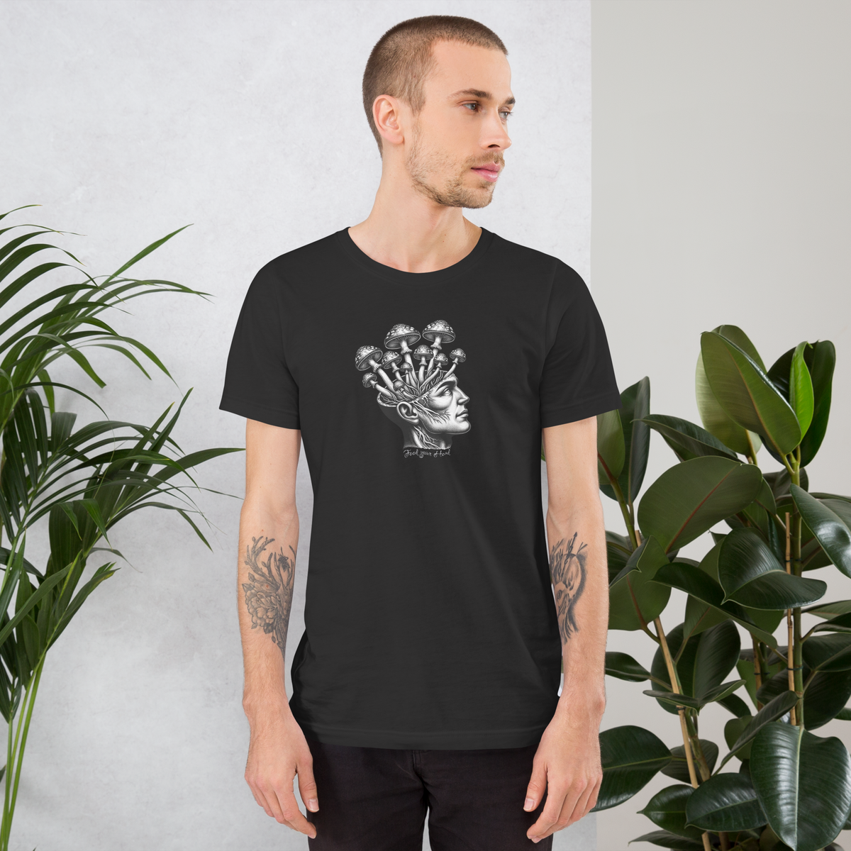 Mann trägt graues T-Shirt mit Kopf aus dem Pilze wachsen und Feed Your Head Schriftzug