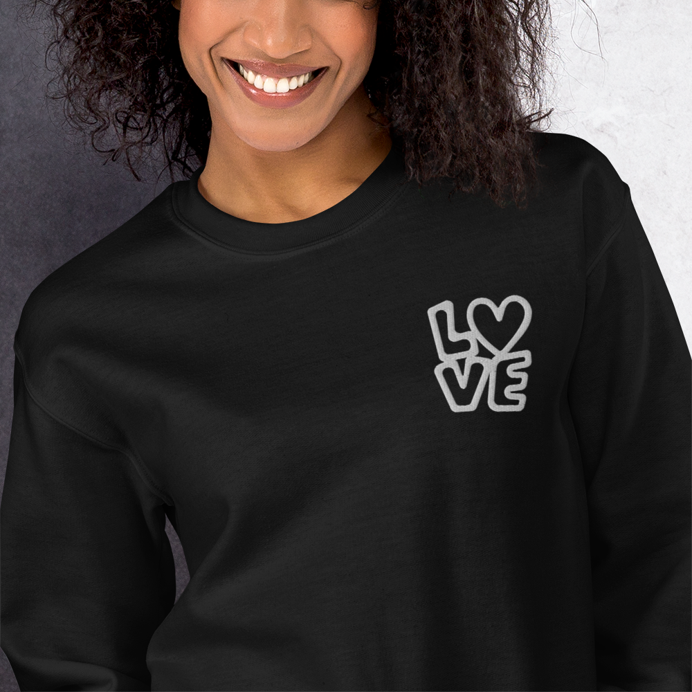 Frau trägt schwarzen Hoodie mit LOVE Stickerei bei dem das O durch ein Herz ersetzt ist